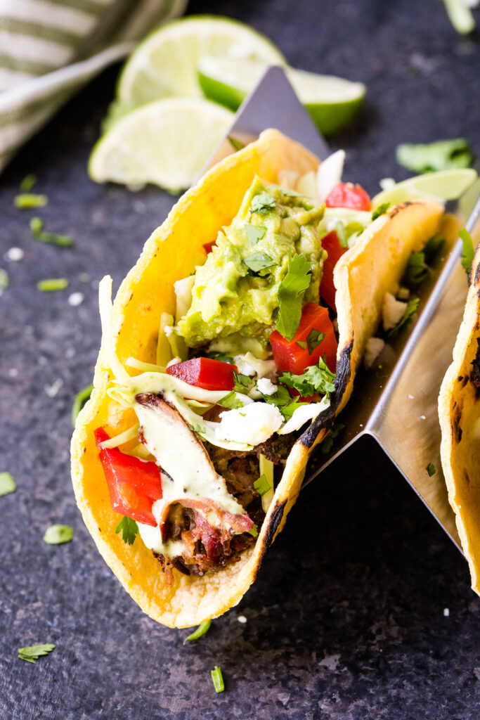 Shredded beef tacos topped with cabbage, guacamole and more