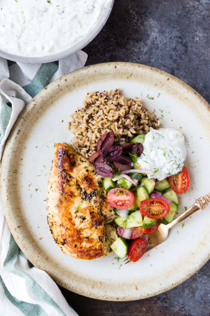 skillet greek chicken with bowl of yogurt in the back ground