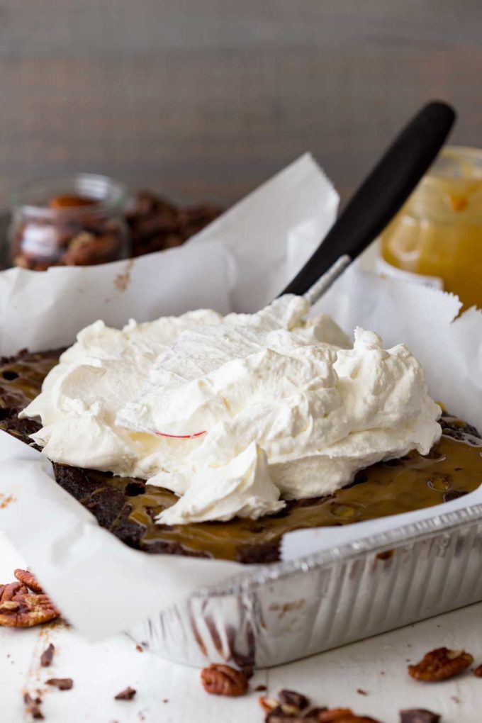 Spreading whipped cream over the easy turtle poke cake!