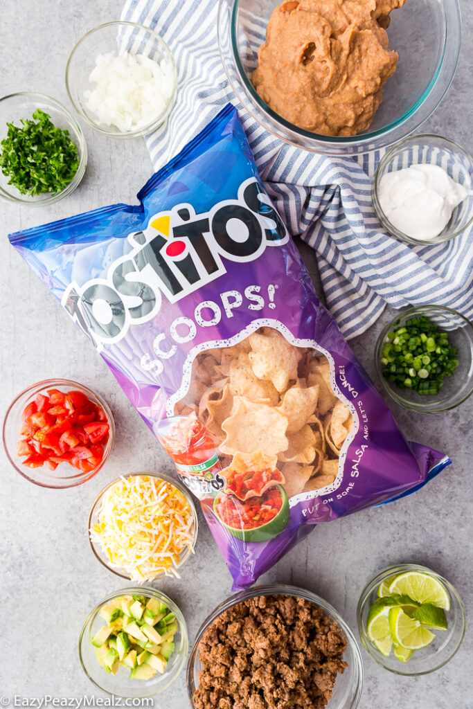 A bag of Tostitos Scoops! and bowls with toppings for taco bites.