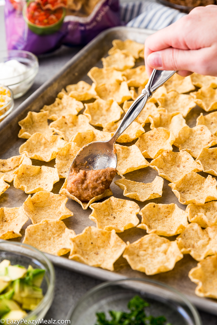 Adding refried beans to each chip