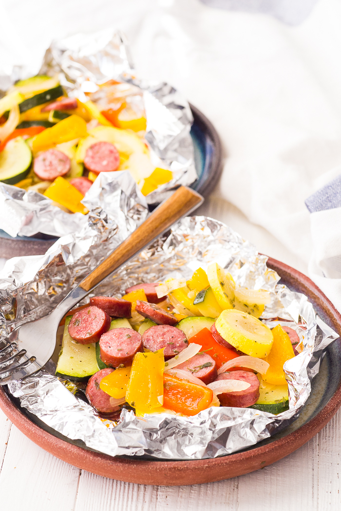 A plate with a foil packet, turkey bratwurst grill pouch