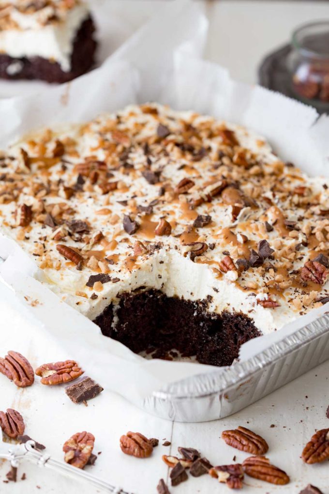 A rich decadent and unique turtle poke cake that is easy to make and topped with toffee as well as caramel, chocolate, and pecans