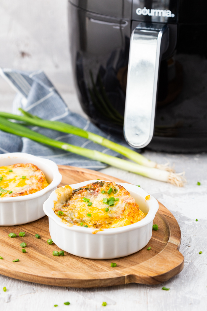 Air fryer egg cups, two ceramic ramekins filled with eggs and vegetables