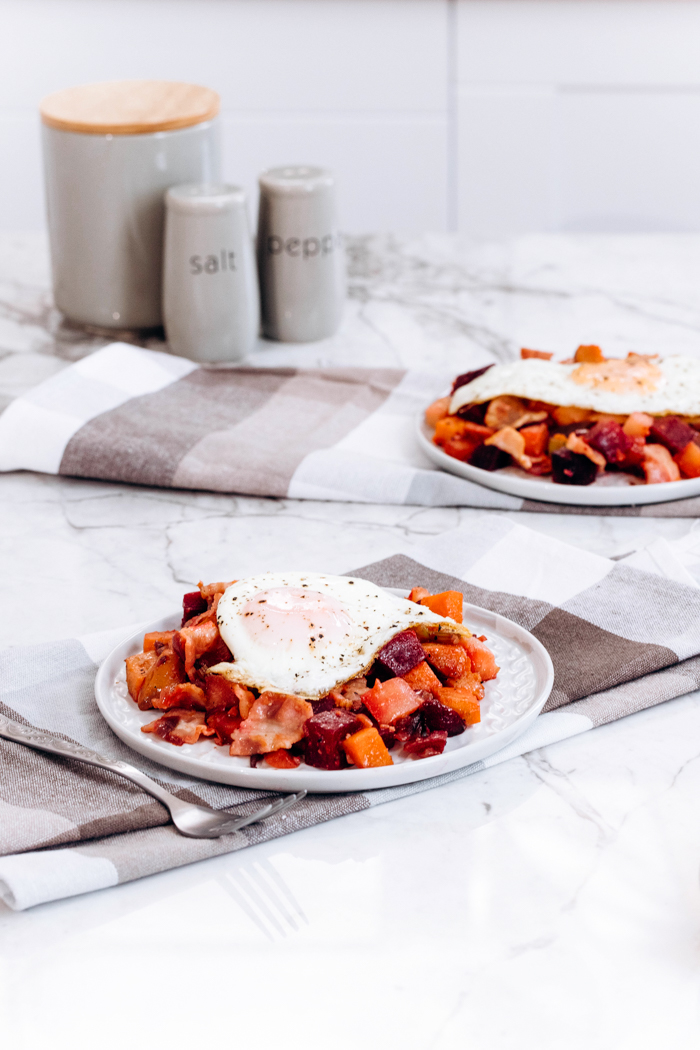 two plates of bacon and eggs veggie hash topped with a fried egg