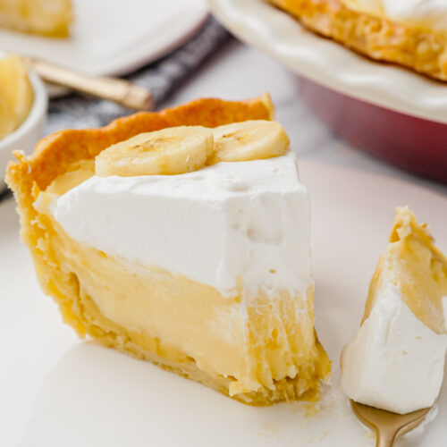 banana creme pie on white plate with fork into it