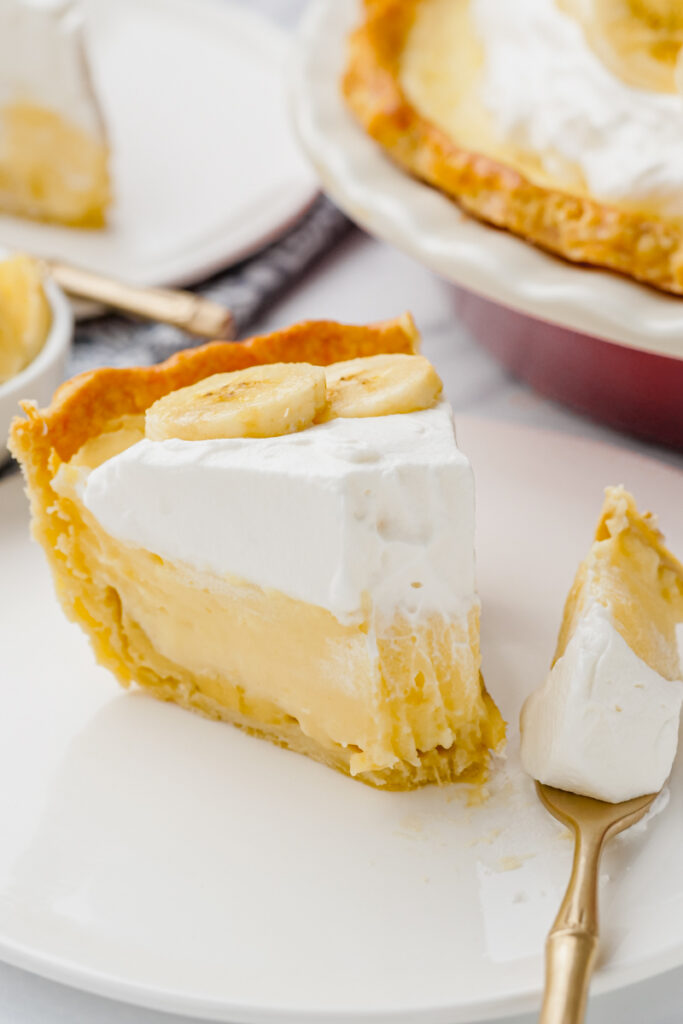 banana creme pie on white plate with fork into it