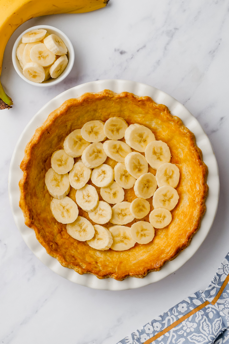 Banana's on the bottom os a pie crust in a tin bowl