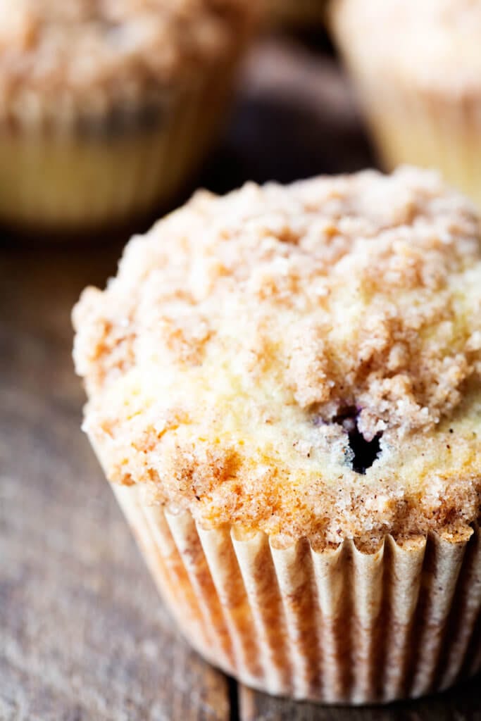 Blueberry Muffins with a crumble topping and wooden background.