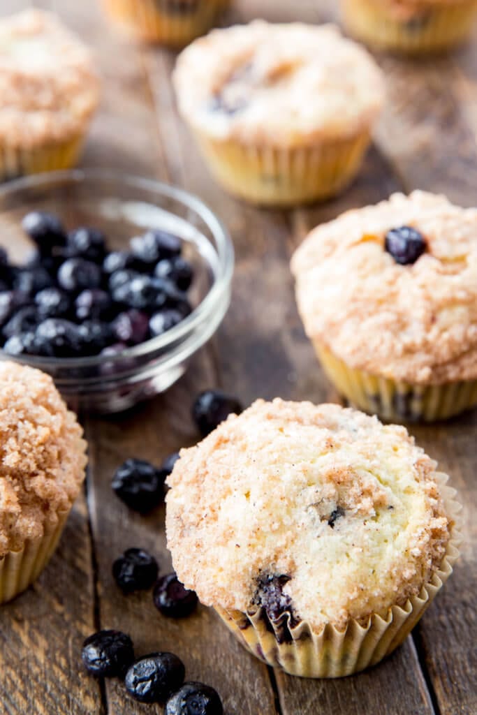 Blueberry Muffins with wood background. Bowl of blueberries next to muffins.
