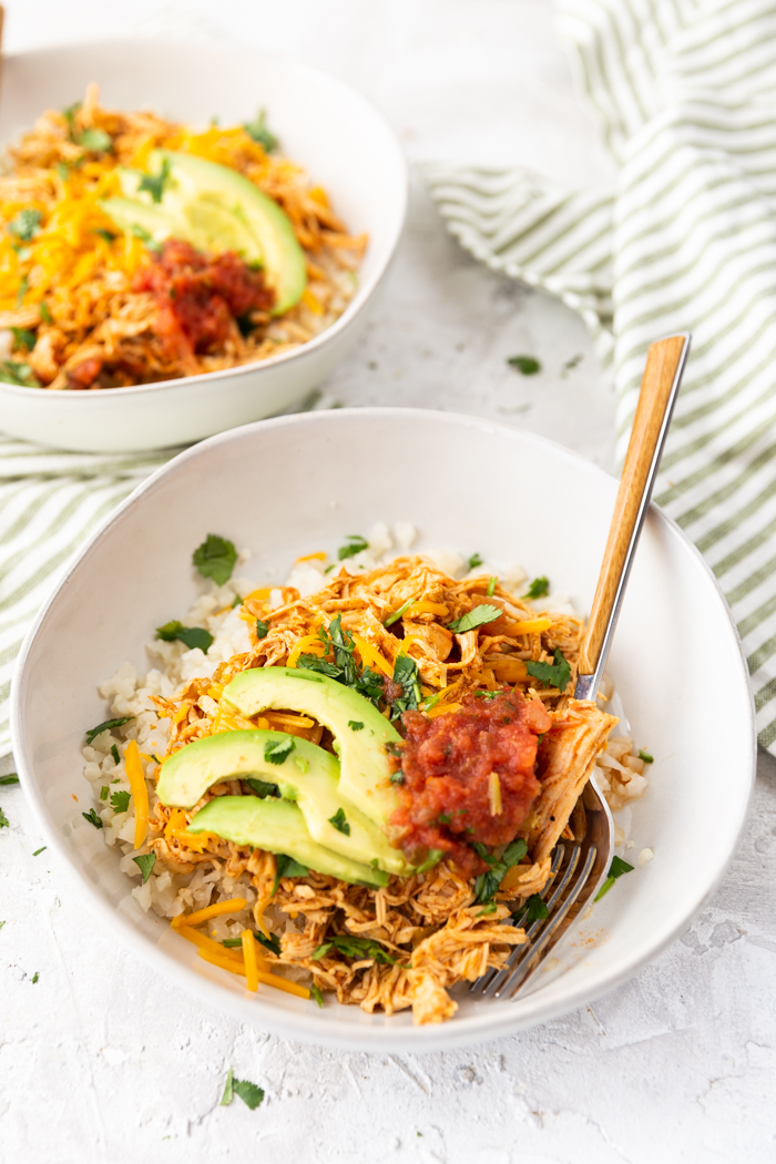 Keto enchilada chicken bowls, topped with avocado and salsa