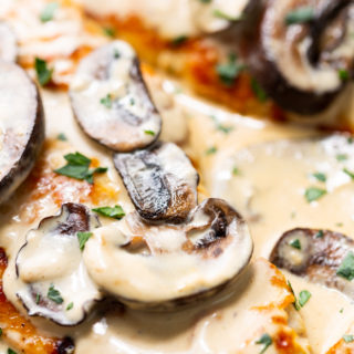Creamy chicken marsala in a skillet with mushrooms and fresh herbs
