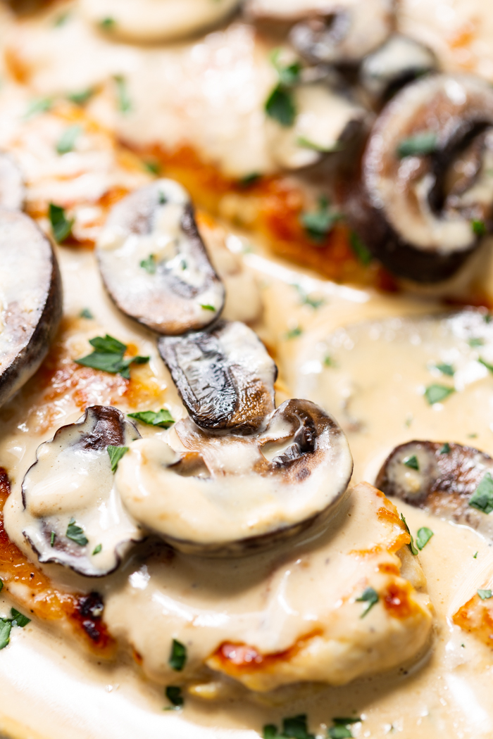 Creamy chicken marsala in a skillet with mushrooms and fresh herbs