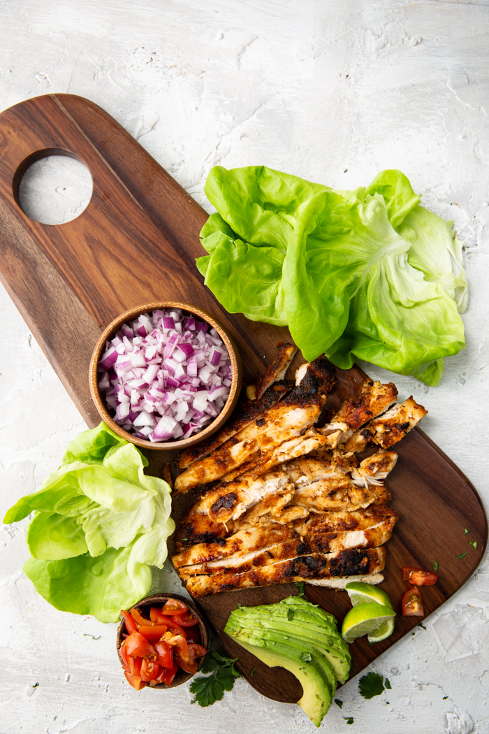 Chicken taco lettuce wrap ingredients on a cutting board. 