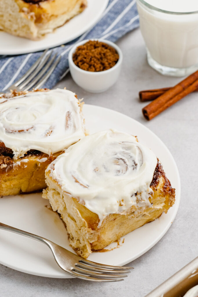 A plate with a fork and two cinnamon rolls