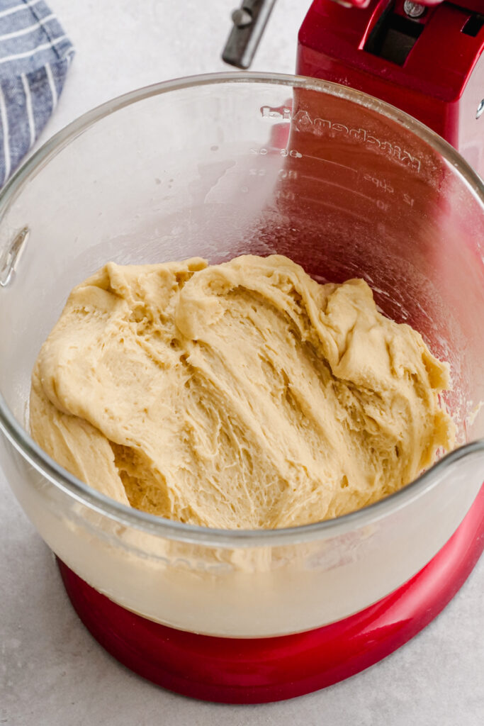 A kitchen aid bowl with cinnamon roll dough. 