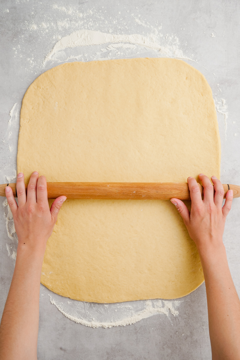 Rolling out cinnamon roll dough on a floured surface