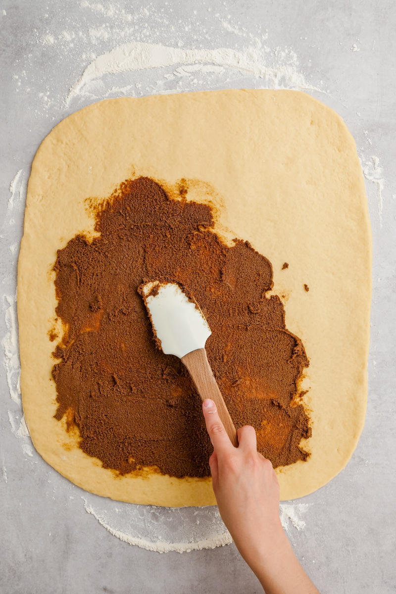 Adding the cinnamon roll filling to the dough