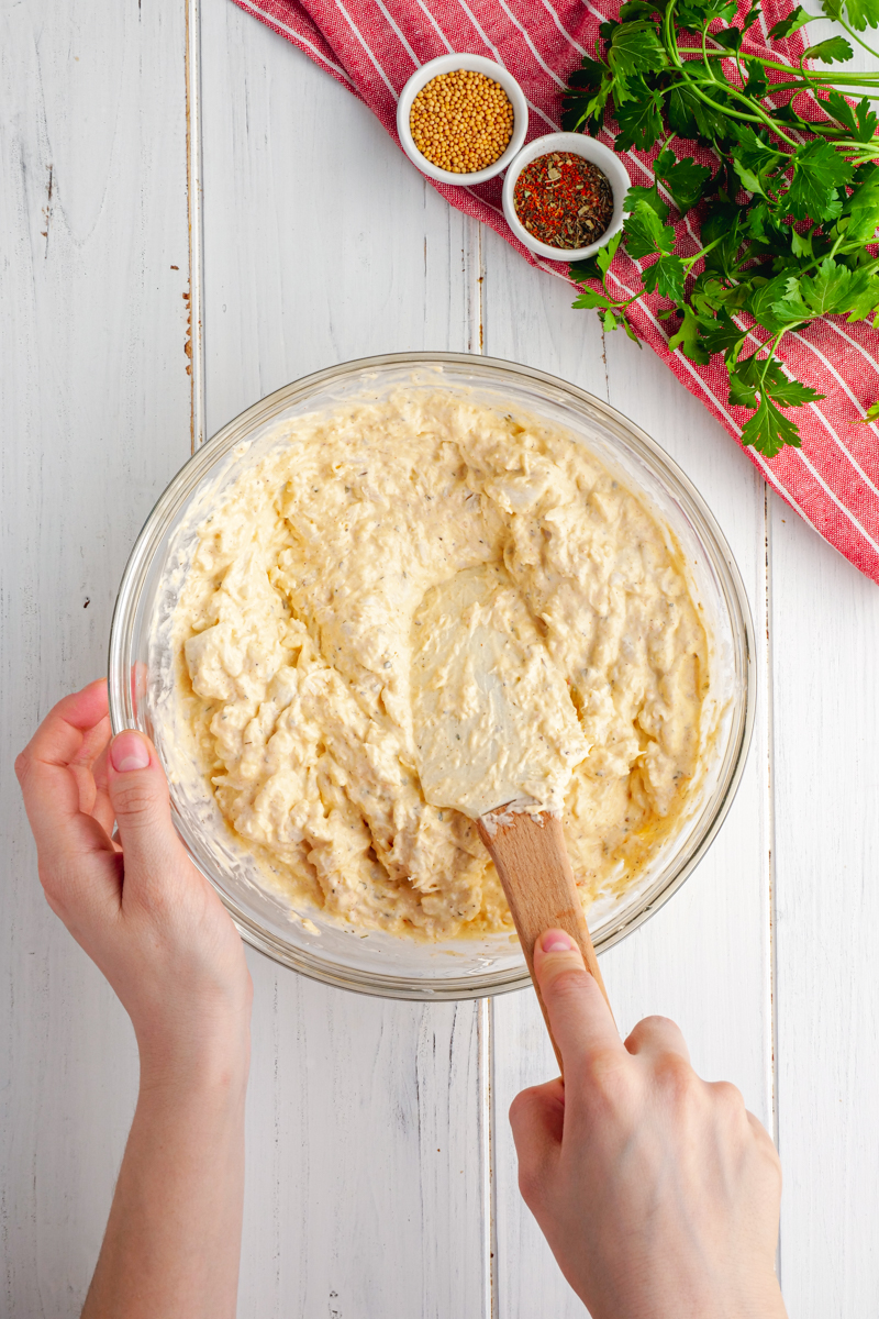 A big glass bowl, with hands and a spatula mixing up your crab dip