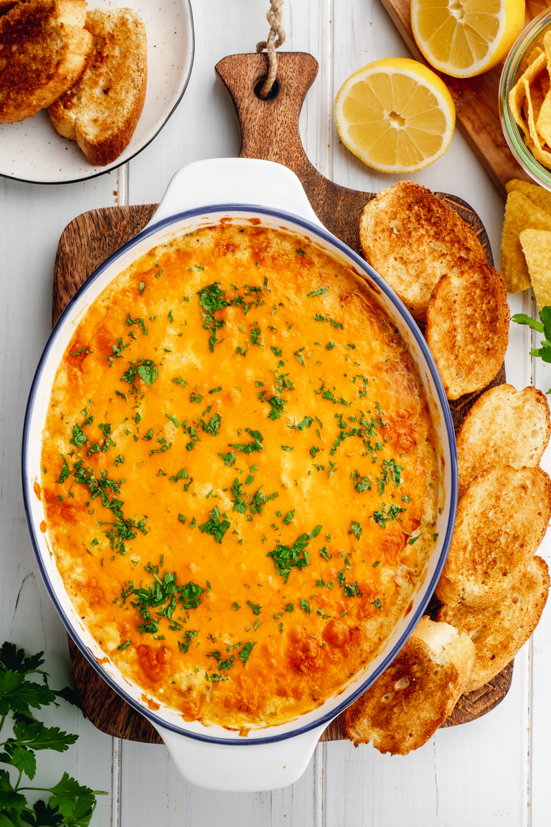 A casserole dish with crab dip, and dippers around it. 