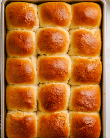 Dinner rolls in a baking sheet, golden brown on top, and light and fluffy on the inside.