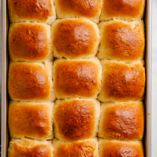 Dinner rolls in a baking sheet, golden brown on top, and light and fluffy on the inside.