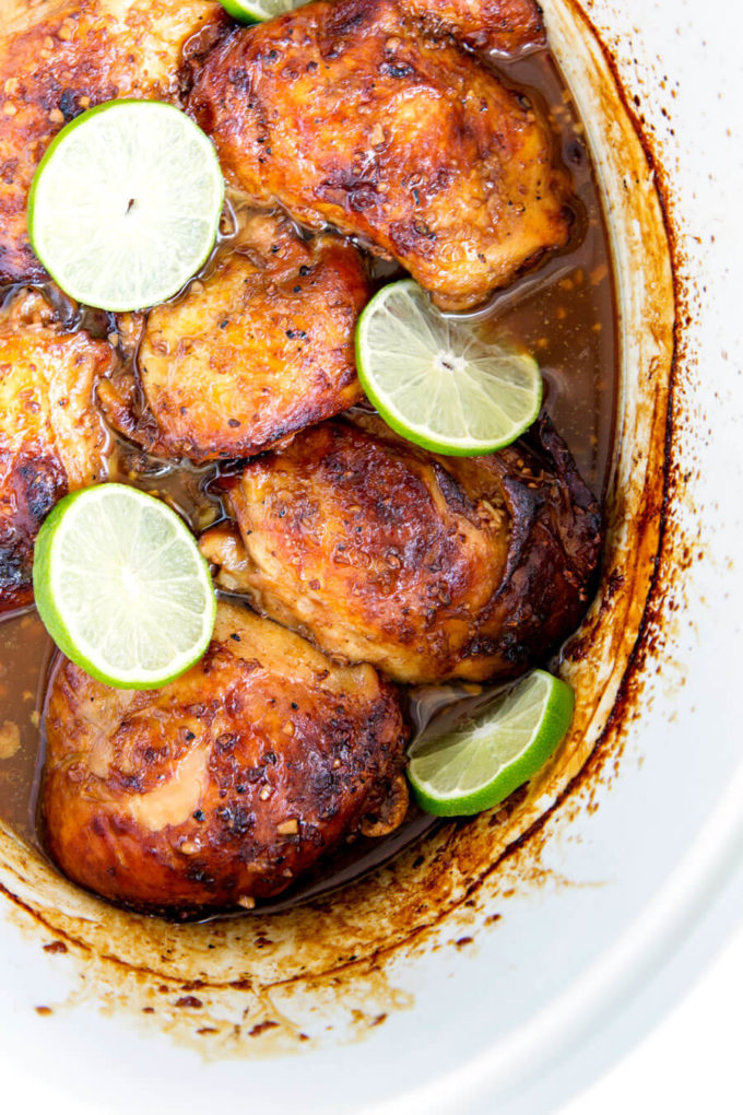 Crockpot Garlic Lime Chicken in marinade with fresh lime slices.