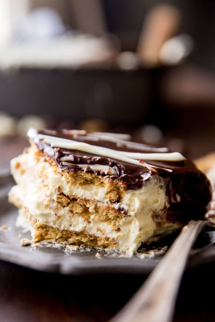 Simple Eclair Ice Box Cake: No baking, no fuss, this easy ice box cake is absolutely delicious and just so fun. Rich chocolate topping, fun vanilla custardy center, and graham crackers. It tastes like an eclair in cake form! And is way easier than baking eclairs.