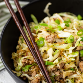 egg roll in a bowl, a black bowl with brown chopsticks. Pork and cabbage.