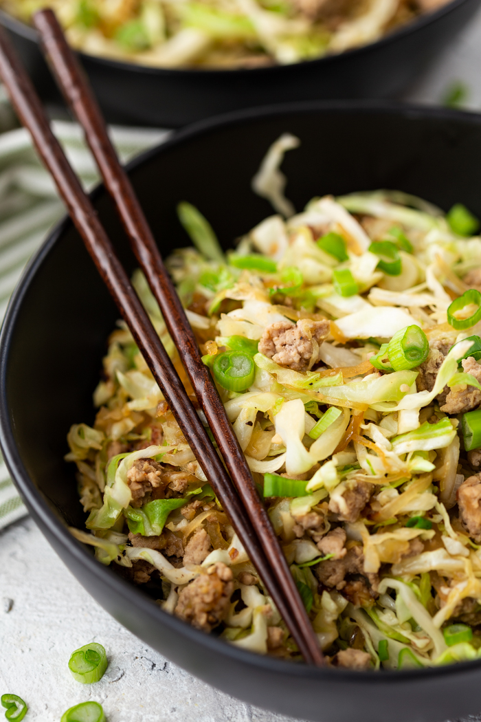 egg roll in a bowl, a black bowl with brown chopsticks. Pork and cabbage.