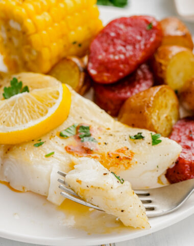 Roasted Halibut Sheet Pan Dinner on white plate with fork into a piece.