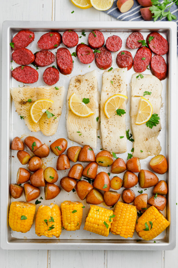 Roasted halibut topped with lemon, and cooked with sausage and potatoes and corn. 