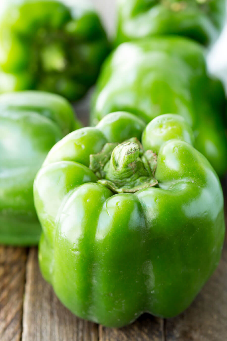 whole green bell peppers on a wooden surface