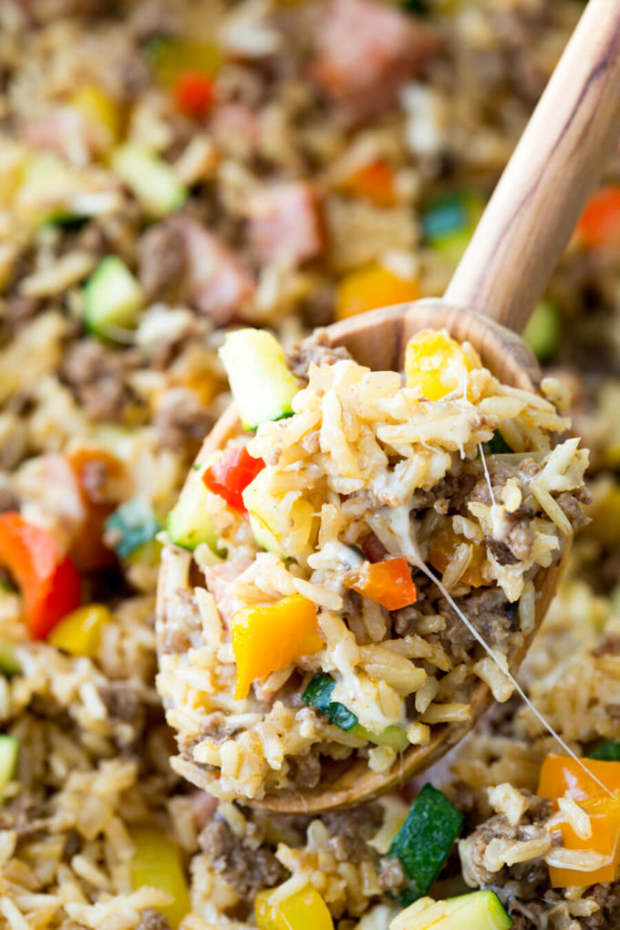 Stuffed pepper filling made from rice, sausage, and vegetable on a wooden spoon