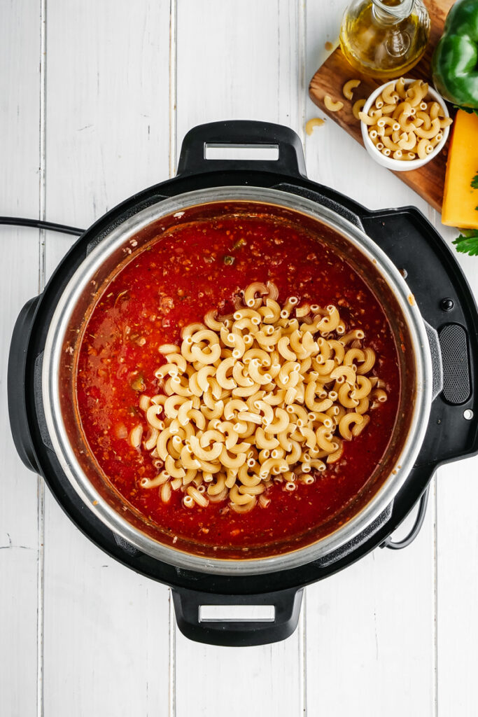 An instant pot with elbow macaroni and other ingredients for American Goulash made in the pressure cooker. 