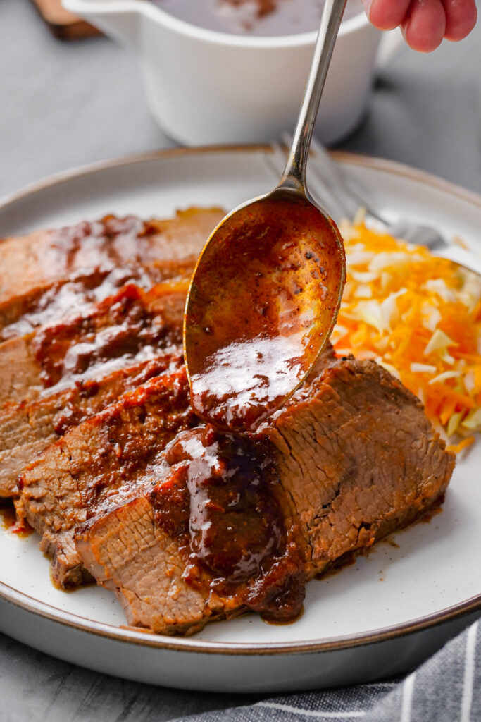 instant pot brisket on white plate with sauce and salad
