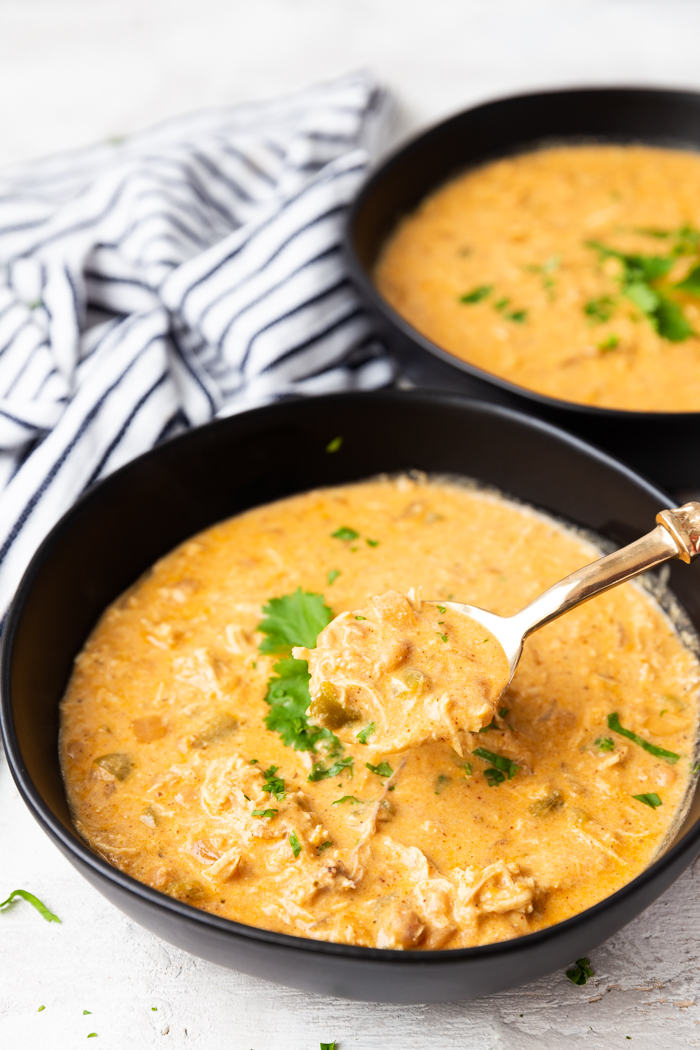 A bowl full of White chicken chili with a spoonfull out