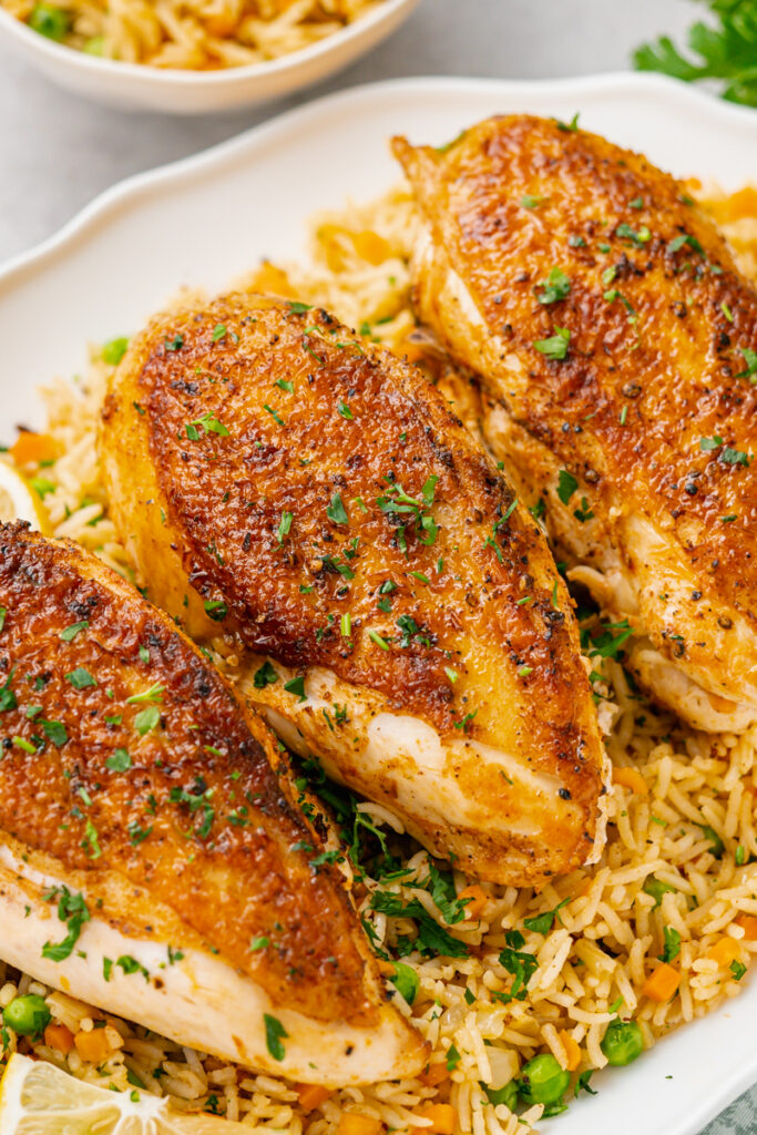 Instant pot chicken and rice, on a white plate, three chicken breasts over rice pilaf 