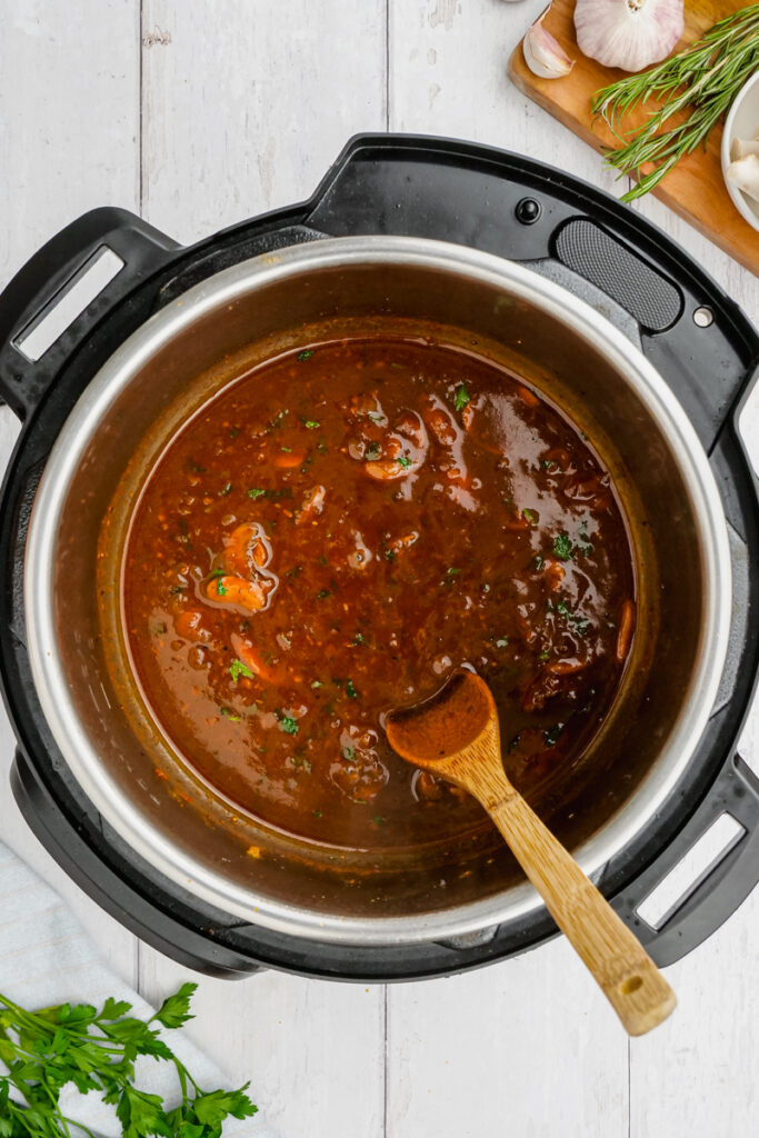 Instant Pot Sirloin Roast Beef with Mushroom Sauce in an instant pot with wooden spoon stirring it all together.