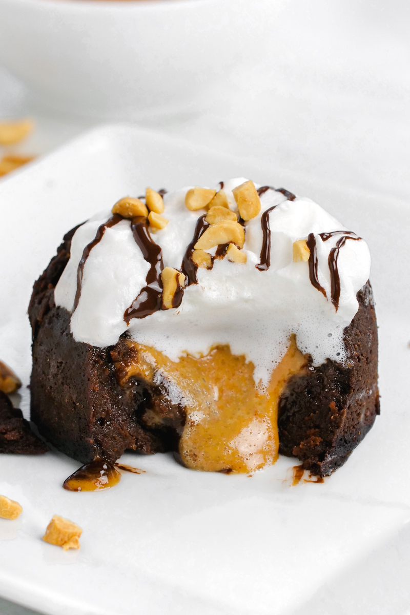 Peanut butter oozing out of a chocolate lava cake with whipped cream, peanuts and chocolate topping 