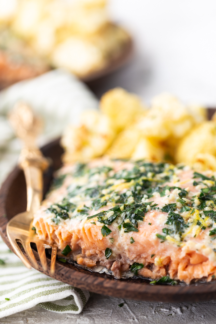 lemon parsley garlic salmon on a brown plate with cauliflower and a bronze fork.