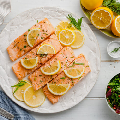 salmon with limes on top and a white plate underneath