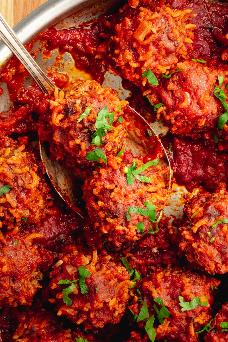 A skillet with porcupine meatballs on a spoon. 