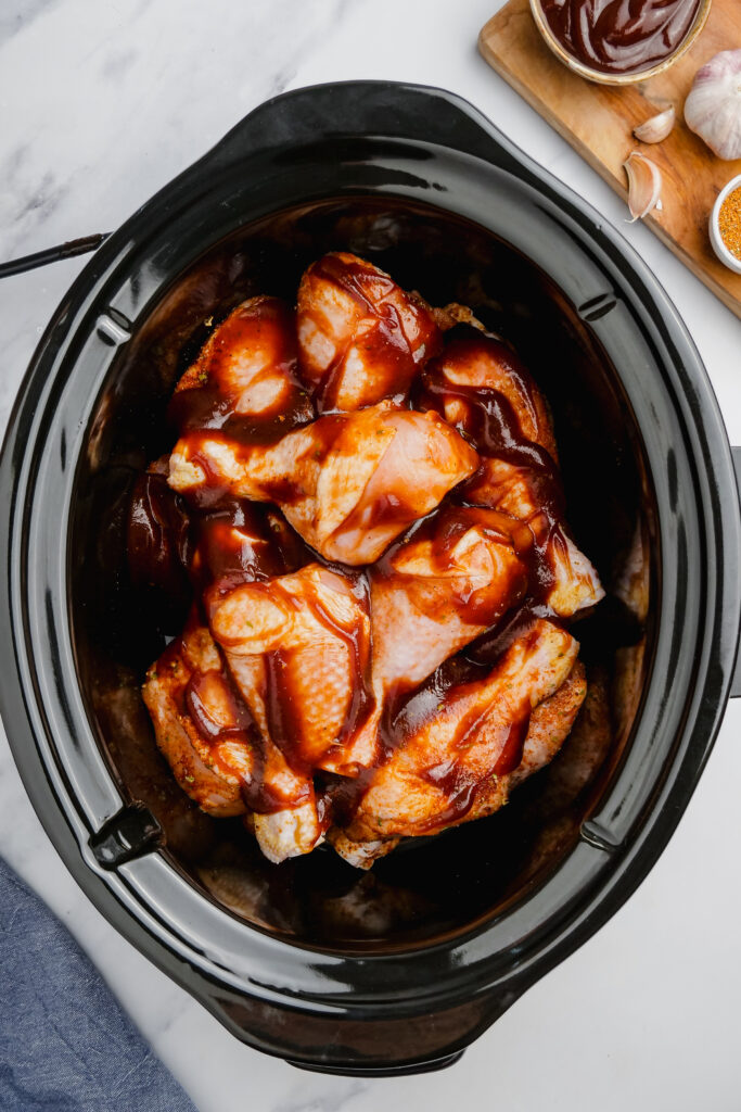 SLow Cooker BBQ Drumsticks in a slow cooker with sauce all over them.
