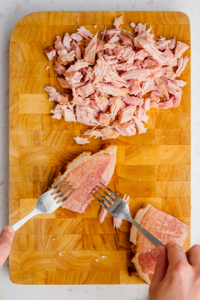 ham form split pea soup on wooden cutting board with forks ripping it apart.