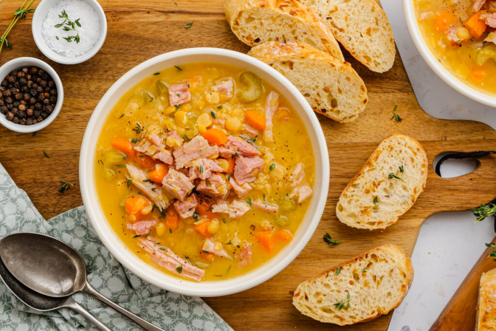 Split Pea Soup in a white bowl with rolls to the side.