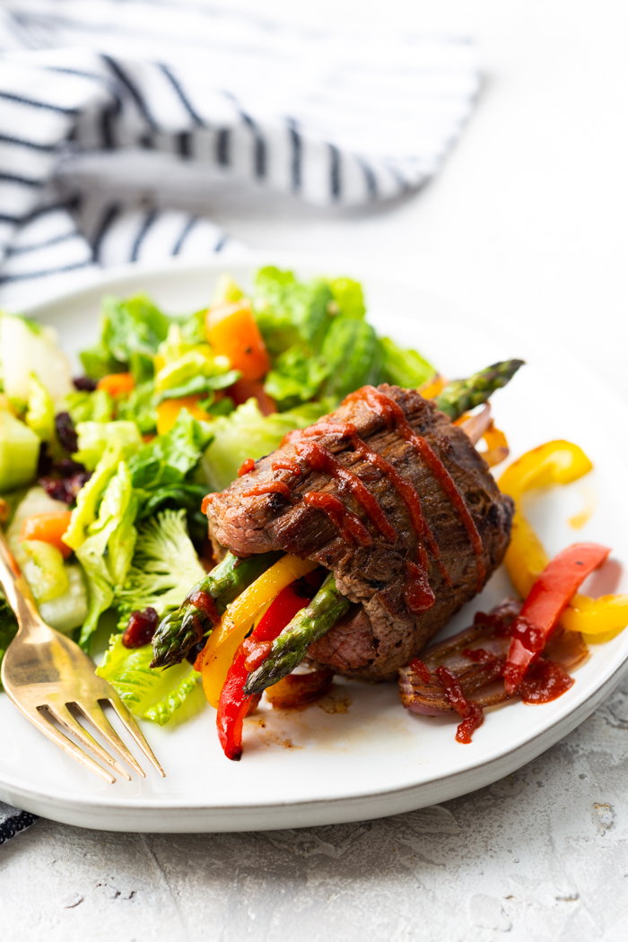 Low carb steak fajitas roll up on a white plate with a green salad