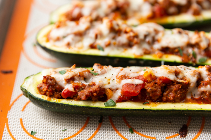 Zucchini boats stuffed with ground beef and tomatoes, topped with mozzarella and fresh herbs. 