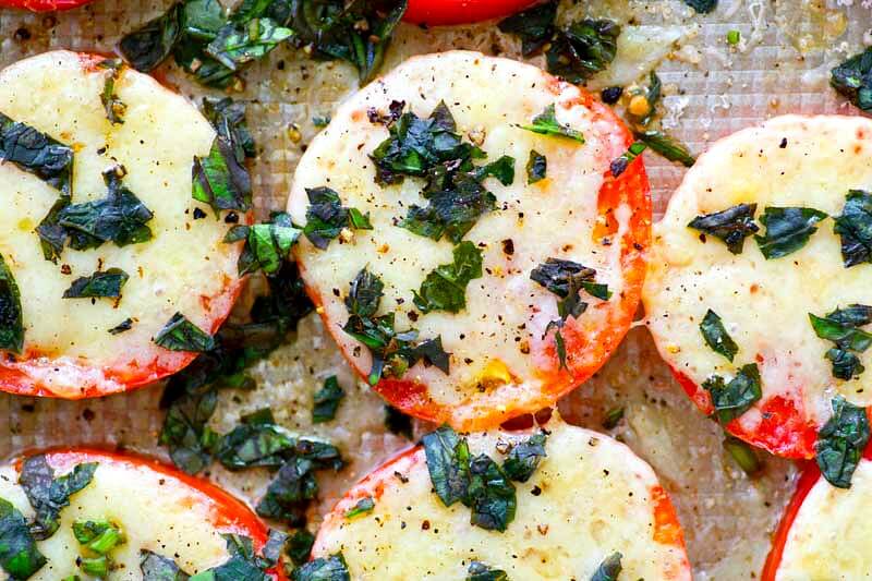 These Baked Parmesan Basil Heirloom Tomatoes are covered in TONS of gooey cheese and fresh basil for one super-simple AND healthier summer side dish! You won't be able to resist eating them straight off the sheet.
