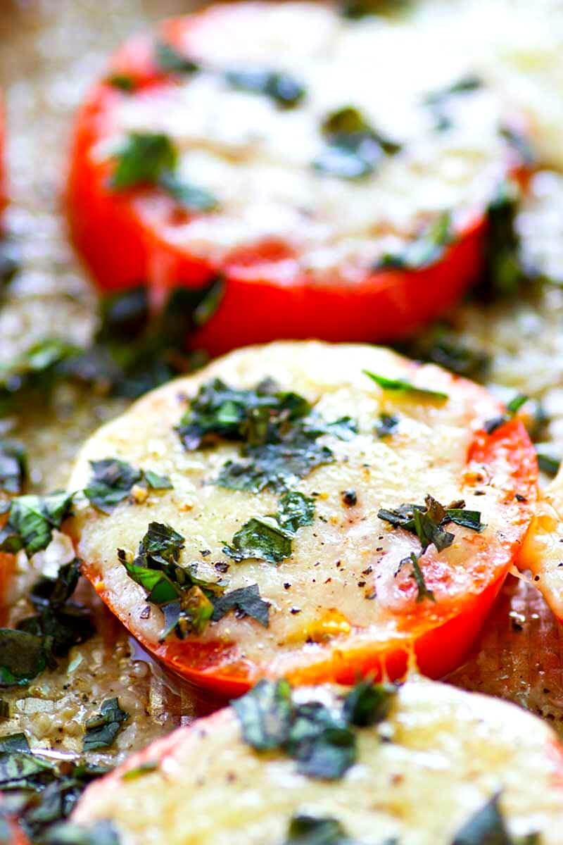 These Baked Parmesan Basil Heirloom Tomatoes are covered in TONS of gooey cheese and fresh basil for one super-simple AND healthier summer side dish! You won't be able to resist eating them straight off the sheet.